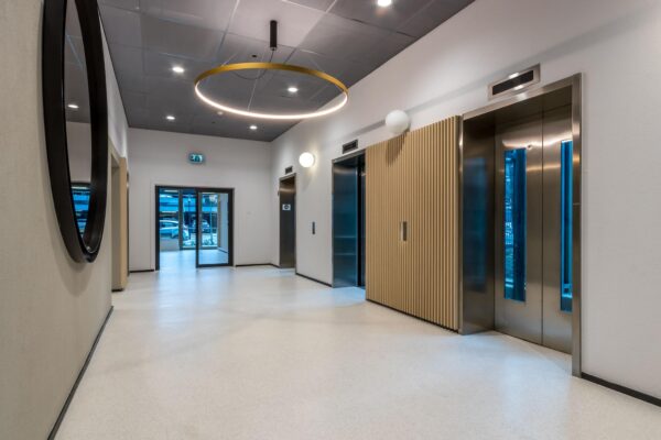 Moderne en strak vormgegeven liftlobby aan de Vliegend Hertlaan met twee liften en een opvallende ronde plafondlamp.